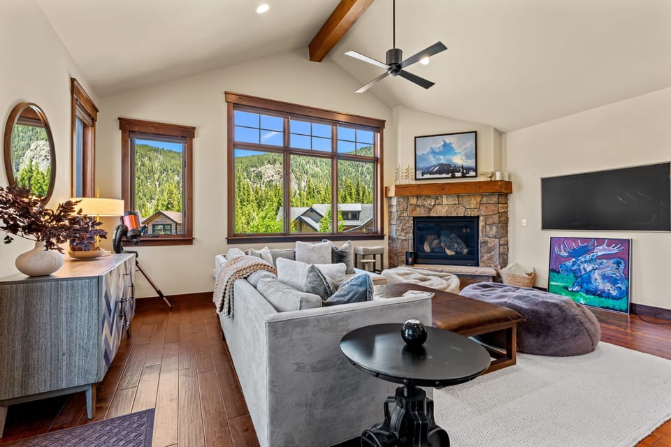 Settle into plush seating beside a stone fireplace, as mountain views fill the windows and vaulted ceilings open the space around you—your cozy retreat awaits.