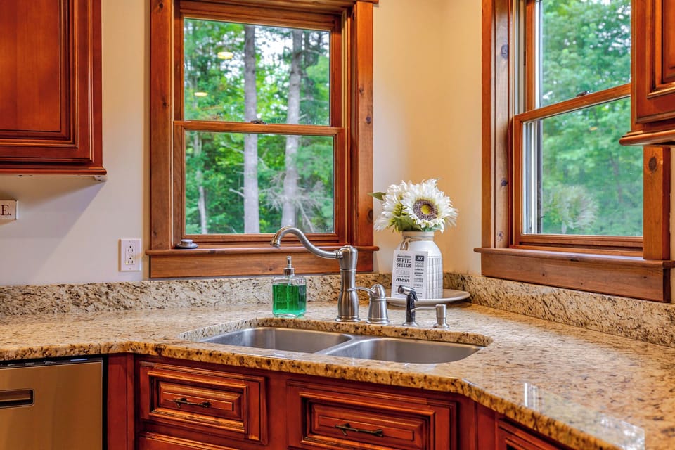 Prepare meals with ease in the fully equipped kitchen, where granite countertops, rich wood cabinetry, and peaceful forest views make cooking a pleasure.