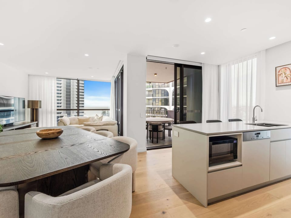 Open living and dining, with the ocean framed at the end of the room.