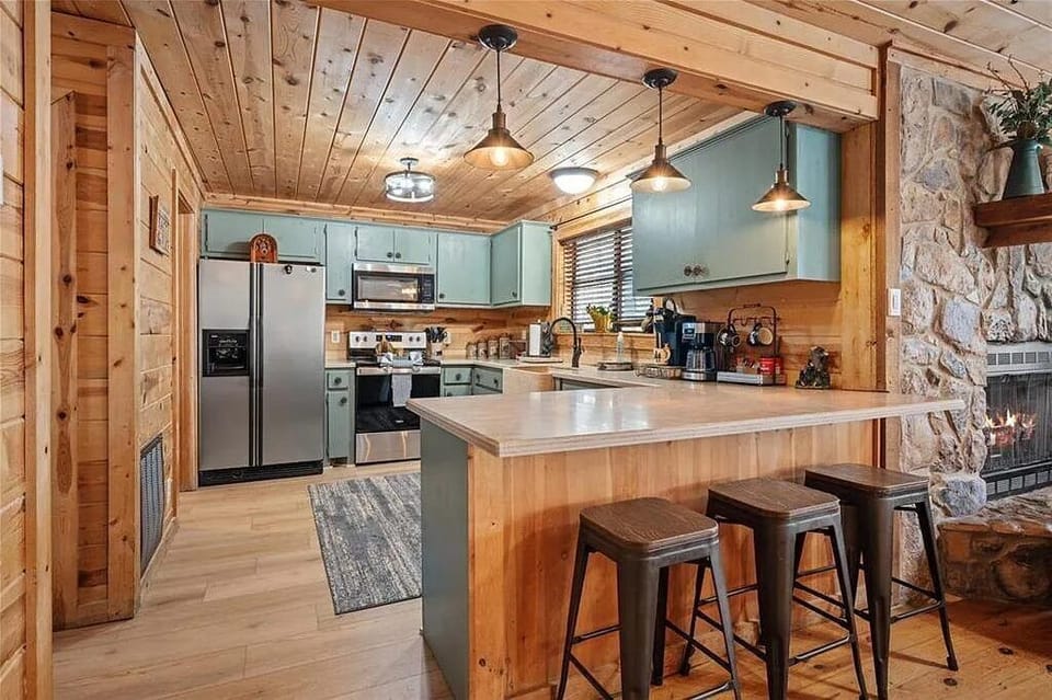 Gather in your inviting kitchen with rustic wood beams, turquoise cabinets, and a spacious island—perfect for sharing meals and making memories by the cozy fireplace.