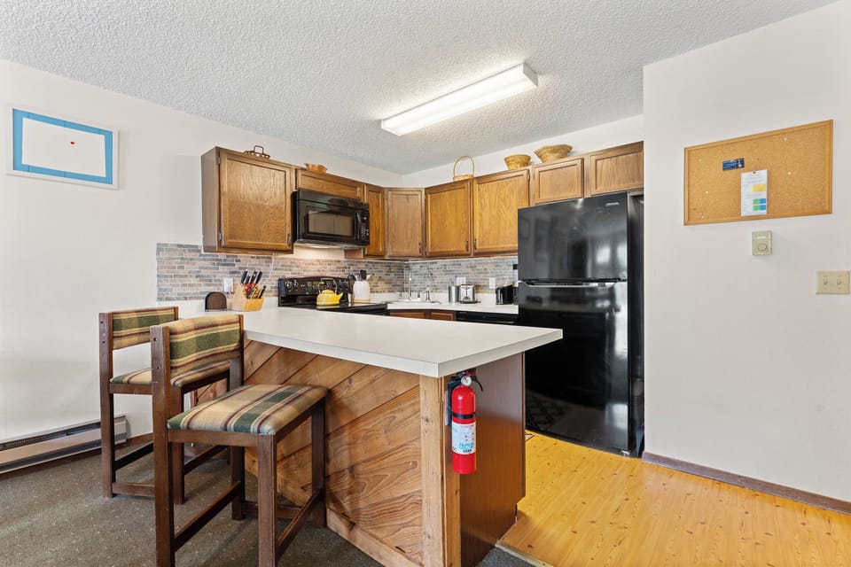 Your fully equipped kitchen invites you to prepare meals together, with warm wood cabinetry, modern appliances, and a cozy breakfast bar for morning coffee or casual dining.