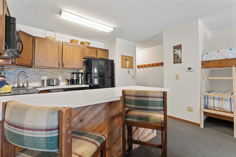 Your cozy retreat features a fully equipped kitchenette with modern appliances and a welcoming dining nook, plus comfortable bunk beds for restful nights after your mountain adventures.