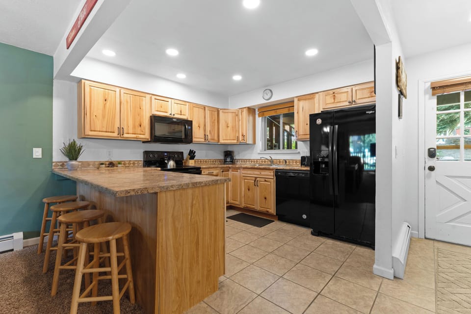Your spacious kitchen features warm wood cabinetry, granite countertops, a large island with bar seating, and full-size appliances—perfect for cooking meals together or enjoying morning coffee.