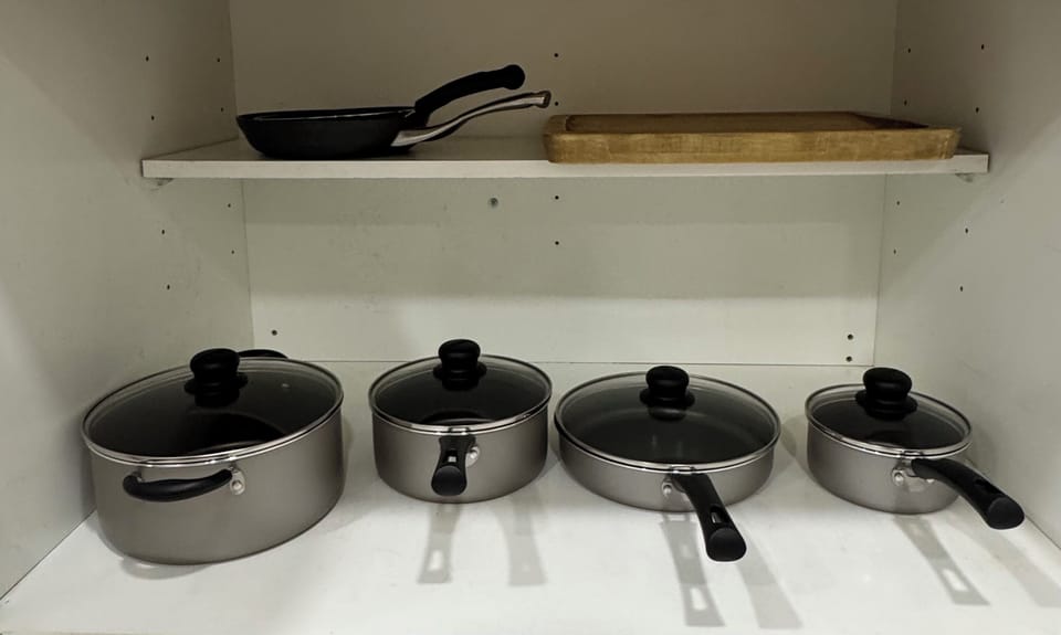 Well-stocked kitchen cabinet with pots, pans, and prep essentials