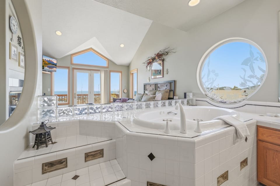 Soak in your private jetted tub while savoring peaceful dunes views through the striking circular window—your spa-like retreat awaits.