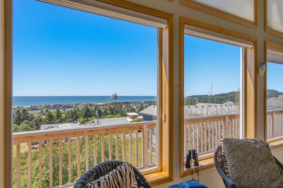 The property offers sweeping coastal and hillside views overlooking the Pacific Ocean, nearby rock formations, and lush forested landscape. The location provides a scenic backdrop near the Oregon coast.