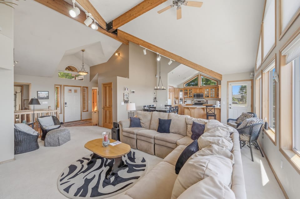 Picture yourself relaxing on this spacious sectional, warmed by natural light streaming through generous windows. The open layout flows seamlessly into the kitchen, perfect for entertaining while enjoying vaulted ceilings and rustic beams overhead.