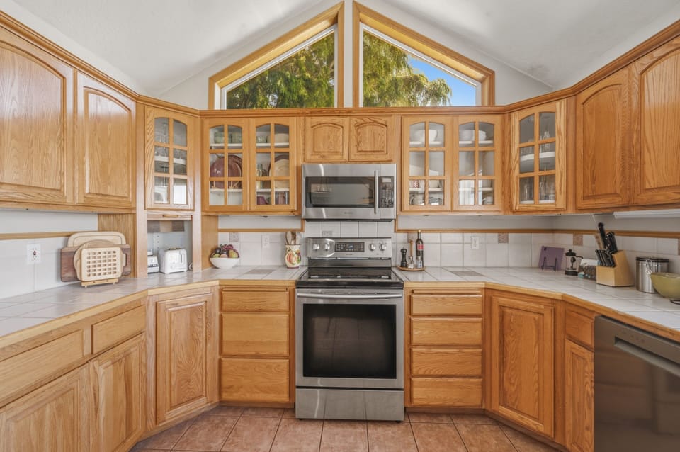 Prepare meals in this fully equipped kitchen with plenty of counter space and natural light streaming through vaulted windows, perfect for your culinary adventures.