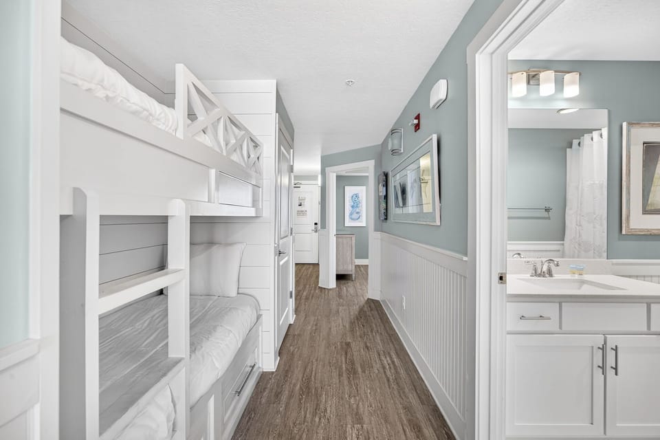 Your beach-styled retreat features cozy built-in bunk beds with crisp white linens and a private en-suite bathroom—perfect for families who want comfortable sleeping spaces and convenient access to everything they need.