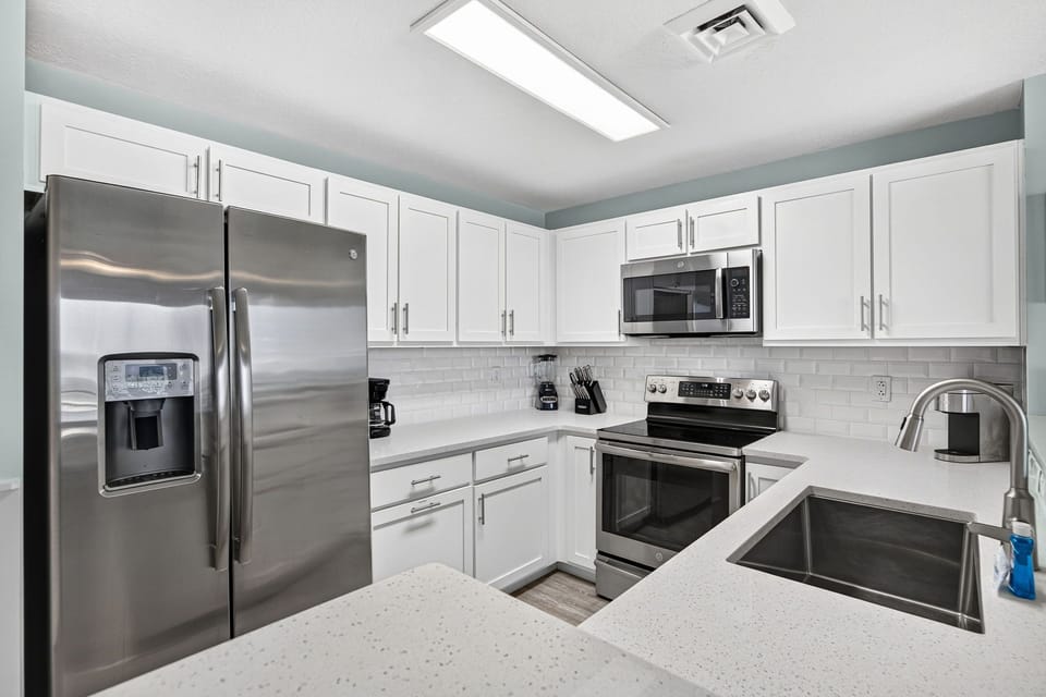 Your fully-equipped kitchen shines with stainless steel appliances, crisp white cabinetry, and plenty of counter space—perfect for preparing meals or sipping morning coffee in style.