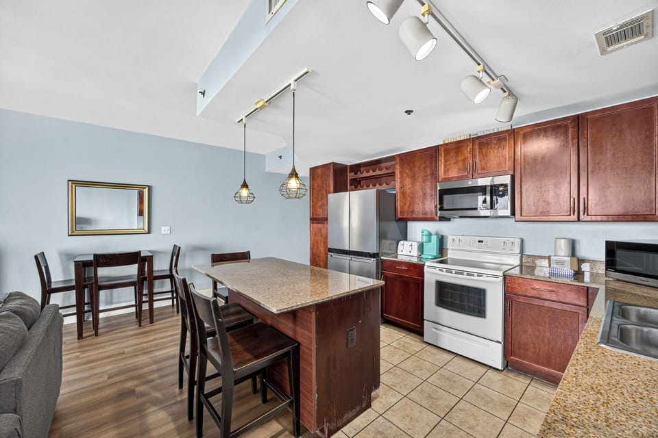 Your fully equipped kitchen features rich cherry cabinets, stainless steel appliances, and a spacious island where you can prepare meals and gather with loved ones in this bright, open space.