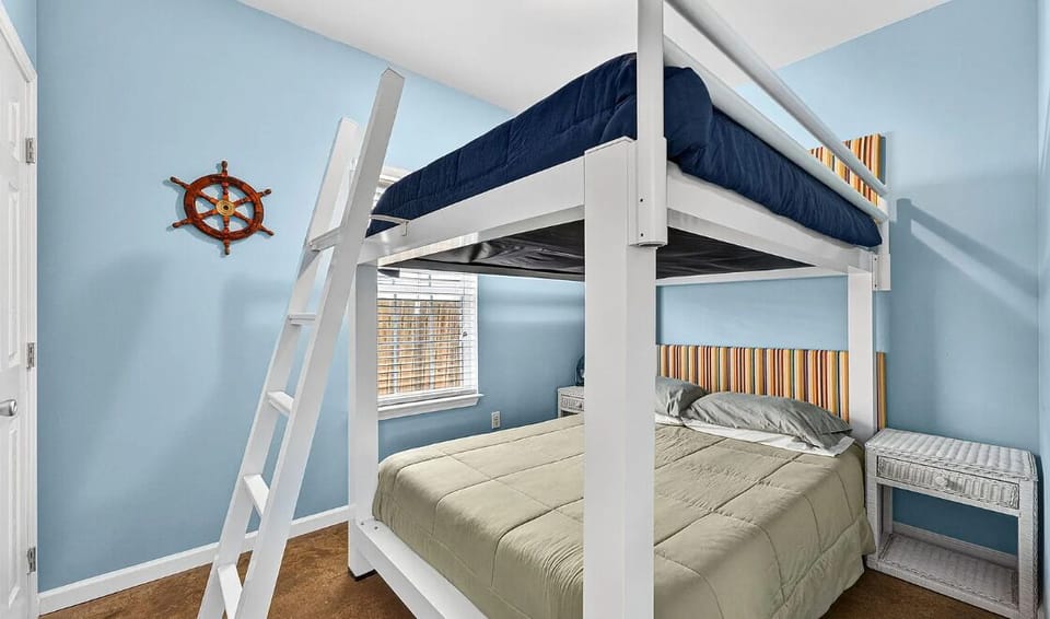 Your kids will love this nautical-themed bunk room with its cozy loft bed and peaceful blue walls, perfect for relaxing after beach adventures.