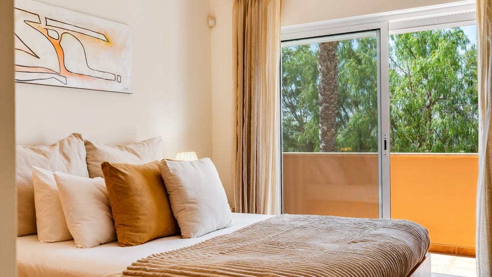 Wake up to the gentle natural light and the fresh air from your private balcony, offering a serene green view to start your day refreshed. This cozy bedroom provides a comfortable retreat after a day of exploration, complete with a bedside lamp for evenin
