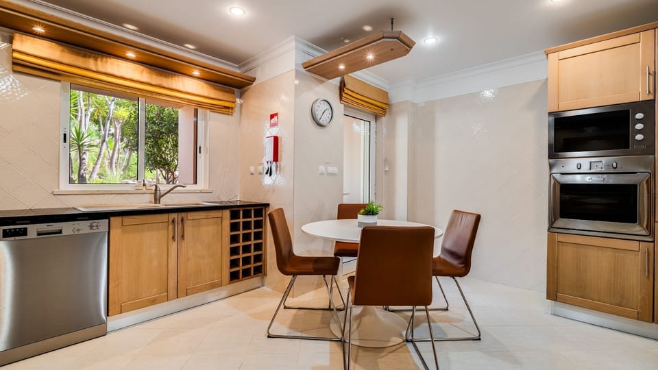 Prepare delicious meals in this well-appointed kitchen, featuring modern appliances and ample counter space, then gather around the cozy dining table for intimate conversations. The window offers a refreshing view of the lush outdoors. #ModernKitchen #Din