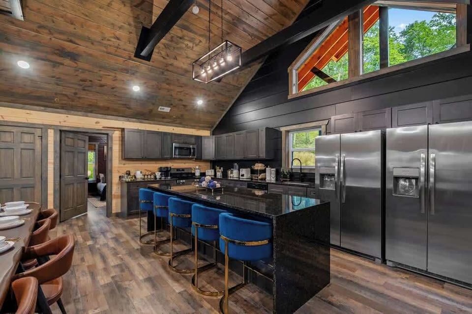 Stylish gourmet kitchen with vaulted wood ceilings and oversized island