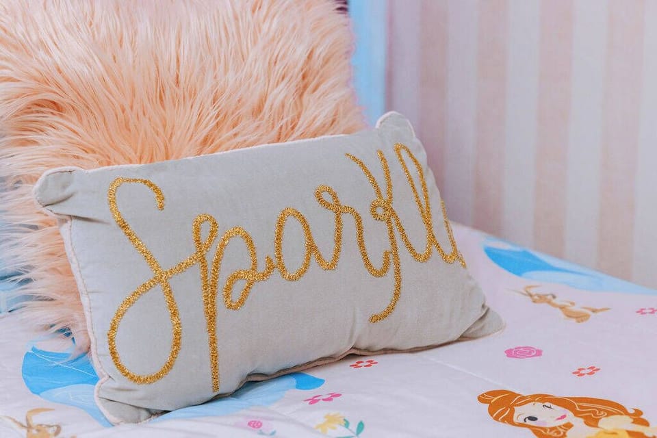 This cozy bed, adorned with a whimsical floral duvet and a fluffy pink pillow, invites relaxation after your adventures. The charming "Sparkle" accent pillow adds a fun touch, making it the perfect spot to unwind and feel at home.