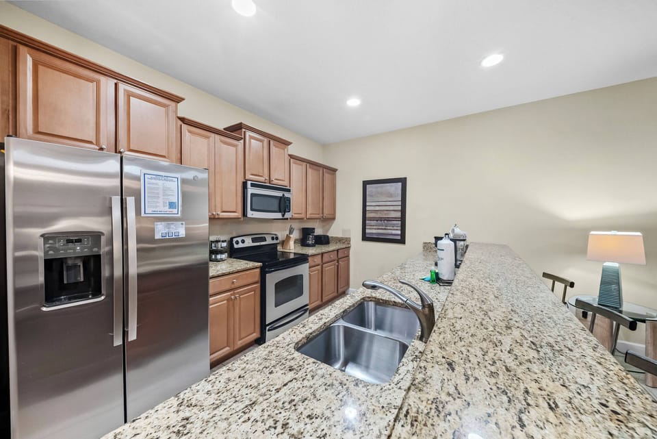 This elegant kitchen boasts beautiful wooden cabinets and a stunning granite countertop paired with stainless steel appliances. Its open layout makes meal prep and entertaining easy, complemented by warm, inviting lighting.