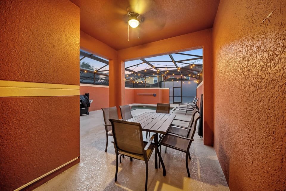 Step outside to our vibrant outdoor dining area with warm orange walls and soft string lights. Relax around a sturdy wooden table, perfect for enjoying evenings with friends and family in a welcoming atmosphere.