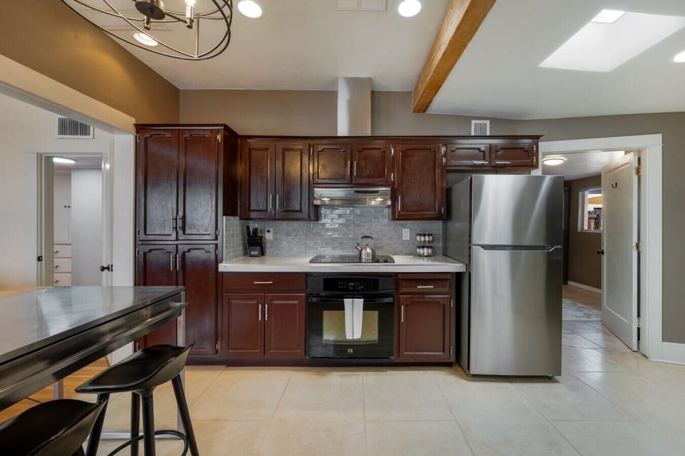 Fully equipped kitchen with cooktop, wall oven, full-size refrigerator, and generous counter space (Note: The bedroom shown in the photo is currently unavailable to guests)
