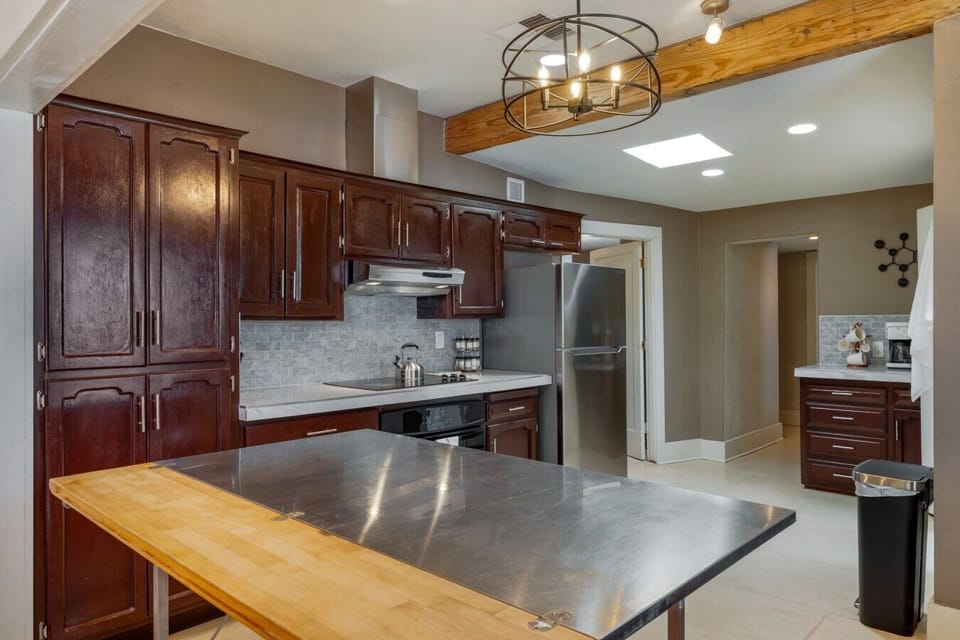 A fully equipped kitchen with rich cherry cabinetry, stainless appliances, and a spacious island with room to gather