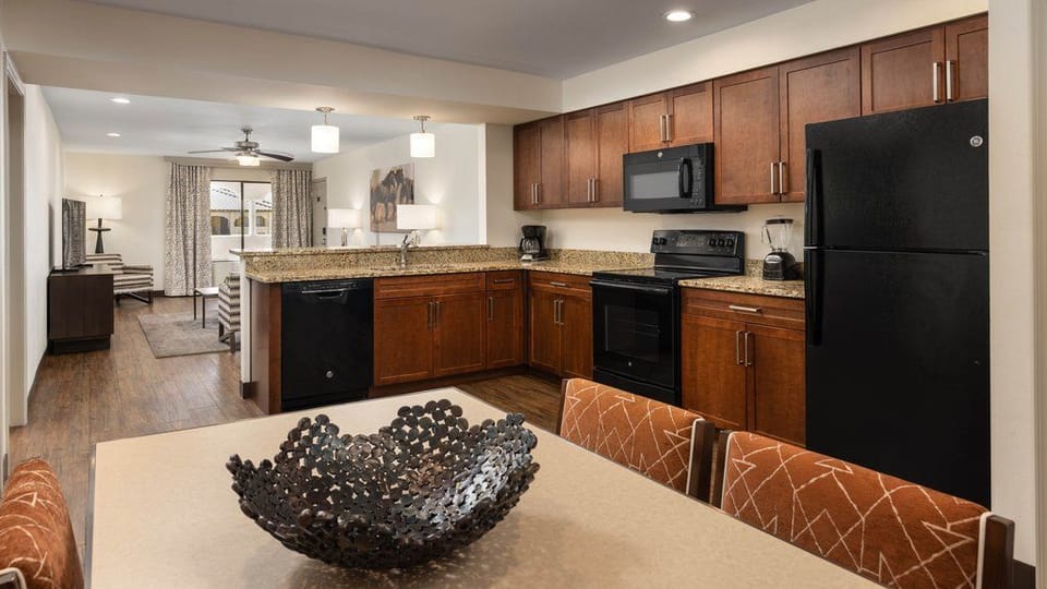 Fully equipped kitchen layout, showcasing sleek appliances and a dining table ready for meals shared together.