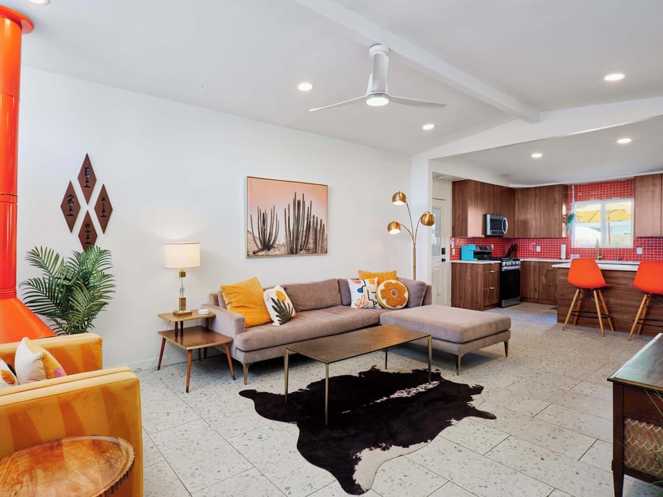 Bright, open living room blending mid-century charm with modern comfort, featuring a Smart TV, iconic fireplace, and spacious seating for gathering and unwinding.