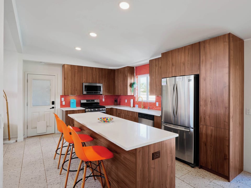 Spacious kitchen featuring stainless steel appliances, generous counter space, and a large island with seating for 3, perfect for gathering over meals and conversation.