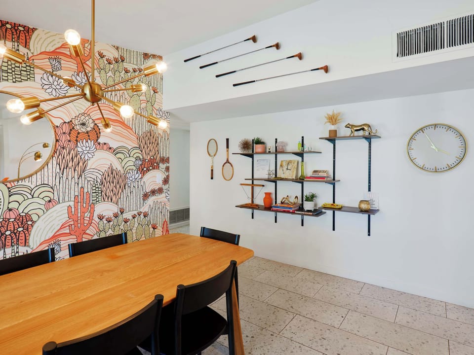 Dining area with seating for 6, a striking desert-inspired feature wall, and direct access to the poolside patio.