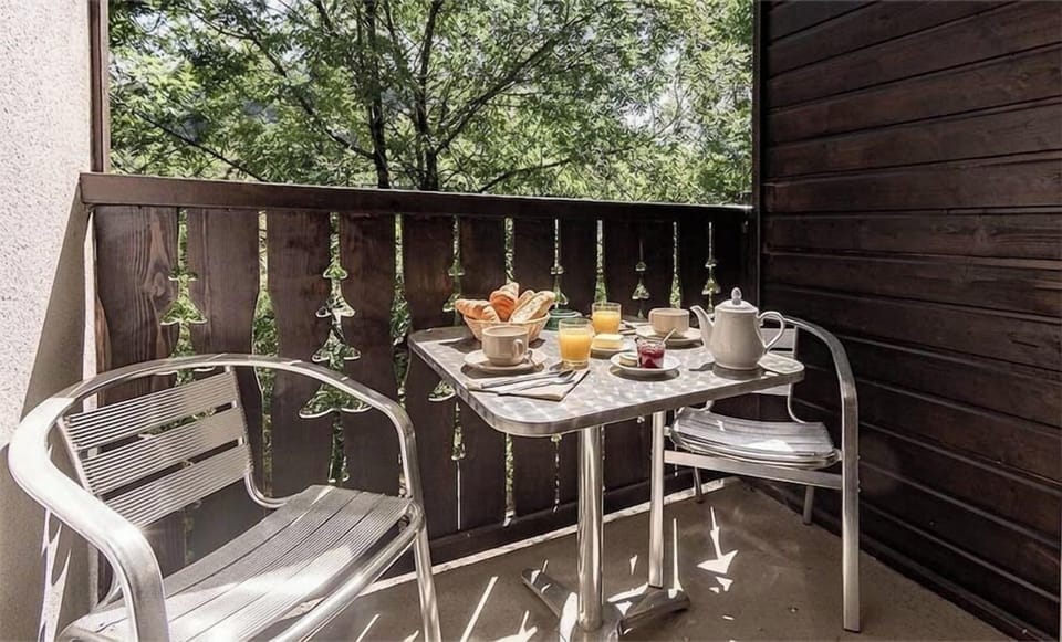 The balcony table looks toward the trees leading up to the Ax-Bonascre gondola, in any season.