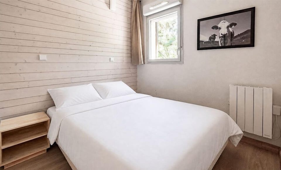 The bedroom's queen bed faces greenery leading up toward Ax 3 Domaines.