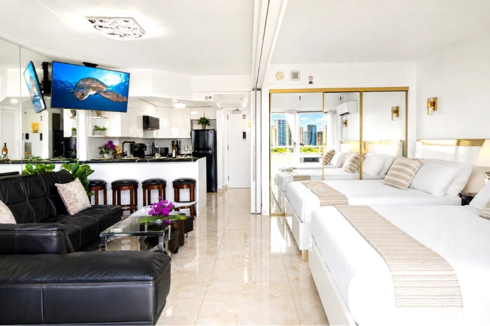 Bright, open-plan living with polished marble floors, plush leather seating, a full breakfast bar, and a wall-mounted Smart TV - the whole suite bathed in island light. ILK-937