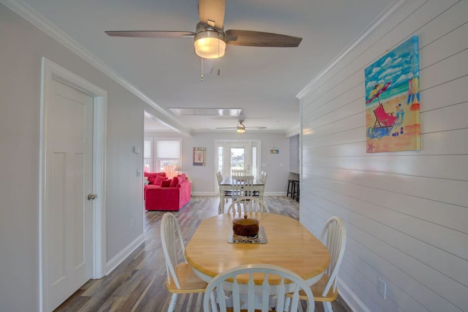 A dining area with a wooden table, white chairs, and a ceiling fan.
