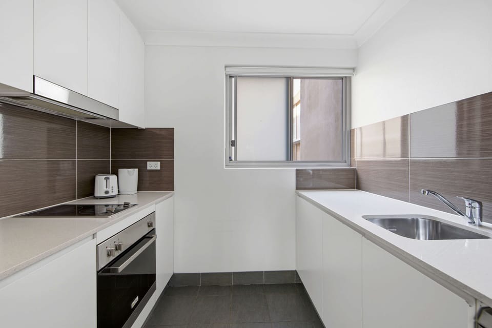 Kitchen featuring cooktop, oven, rangehood and sink