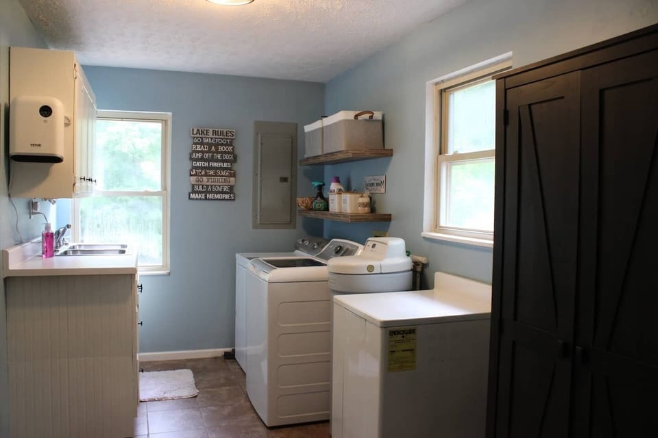 Full laundry area with washer, dryer, utility sink, and storage.