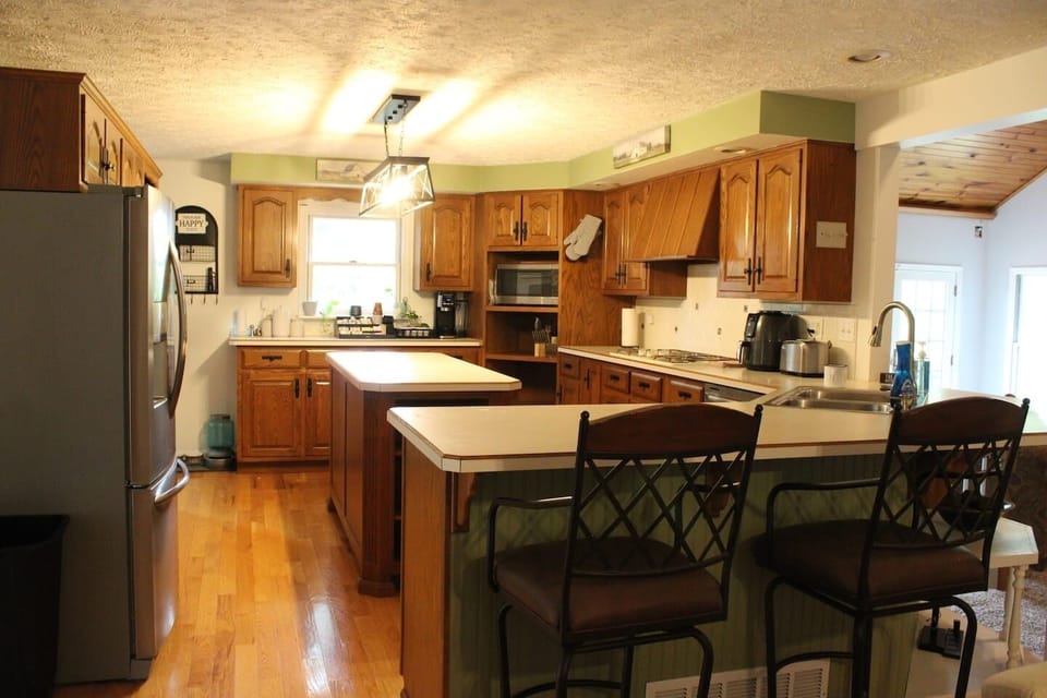 Full kitchen with gas cooktop, double ovens, bar seating, and coffee.