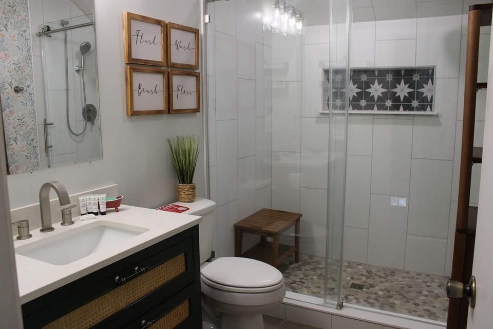 Full bathroom with a glass-enclosed shower, vanity, toilet, and storage.