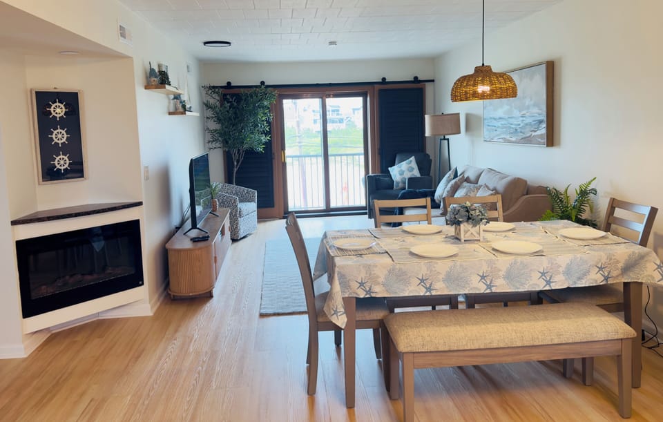 Bright coastal living space with fireplace, dining area, and balcony views