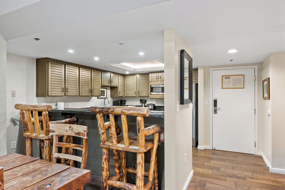 The open kitchen includes a rustic breakfast bar with seating, making it easy to gather for casual meals while staying connected to the dining and living areas.