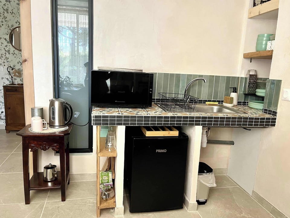 Petite cuisine équipée et fonctionnelle avec four à micro-ondes et bouilloire. 