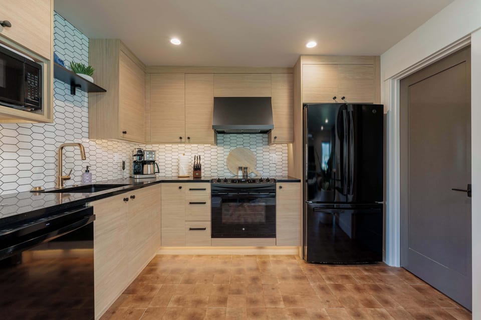 Cook with style in a modern kitchen equipped with sleek dark appliances, crisp tile backsplash, and elegant cabinetry.