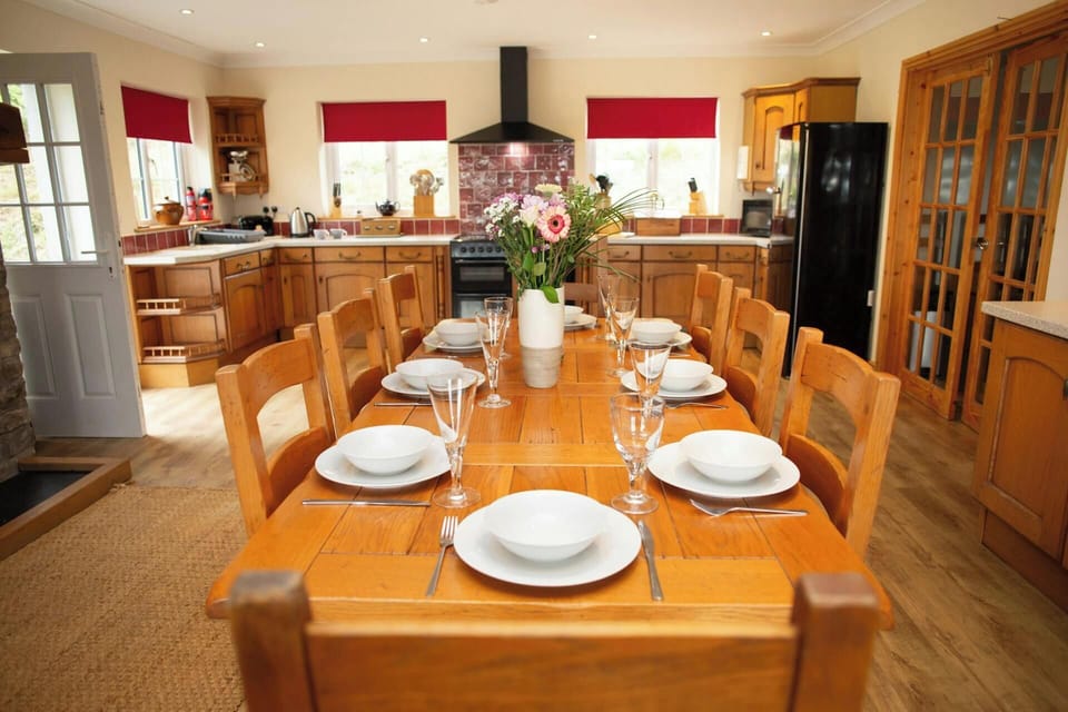 Long wooden table with eight place settings and flowers in a white vase