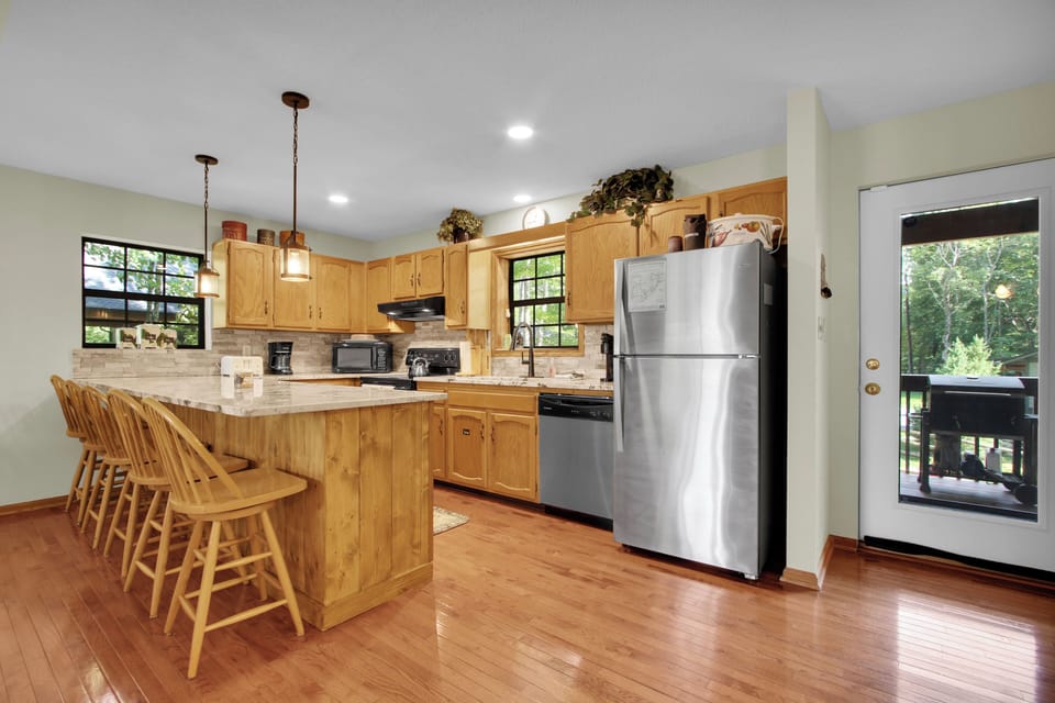 Cook up mountain favorites in the bright wood kitchen, where island seating invites easy conversation and effortless deck access welcomes in fresh air for indoor-outdoor mountain living.