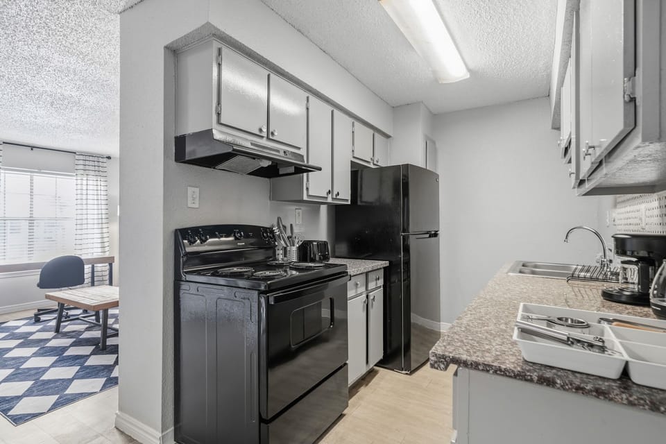 Modern kitchen with sleek black appliances and ample counter space, perfect for preparing meals during your stay.