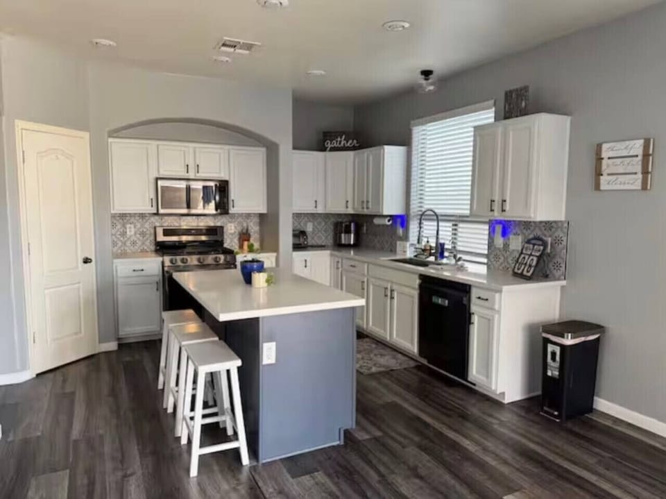 Modern kitchen with granite countertops, white cabinetry and gas stove top