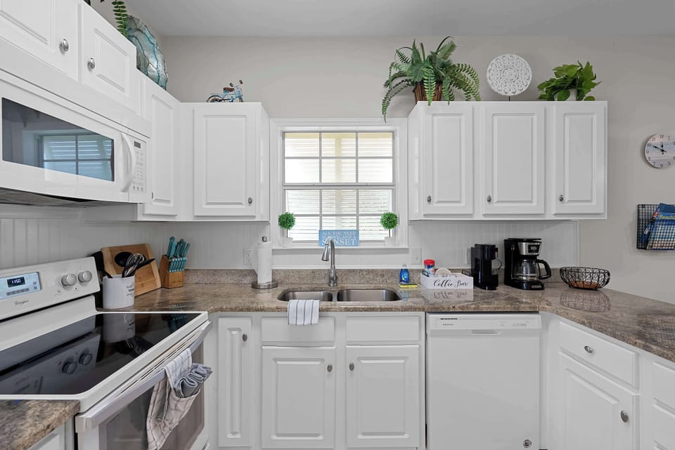 Fully equipped kitchen with generous counter space, dishwasher, double sink, and coffee station.