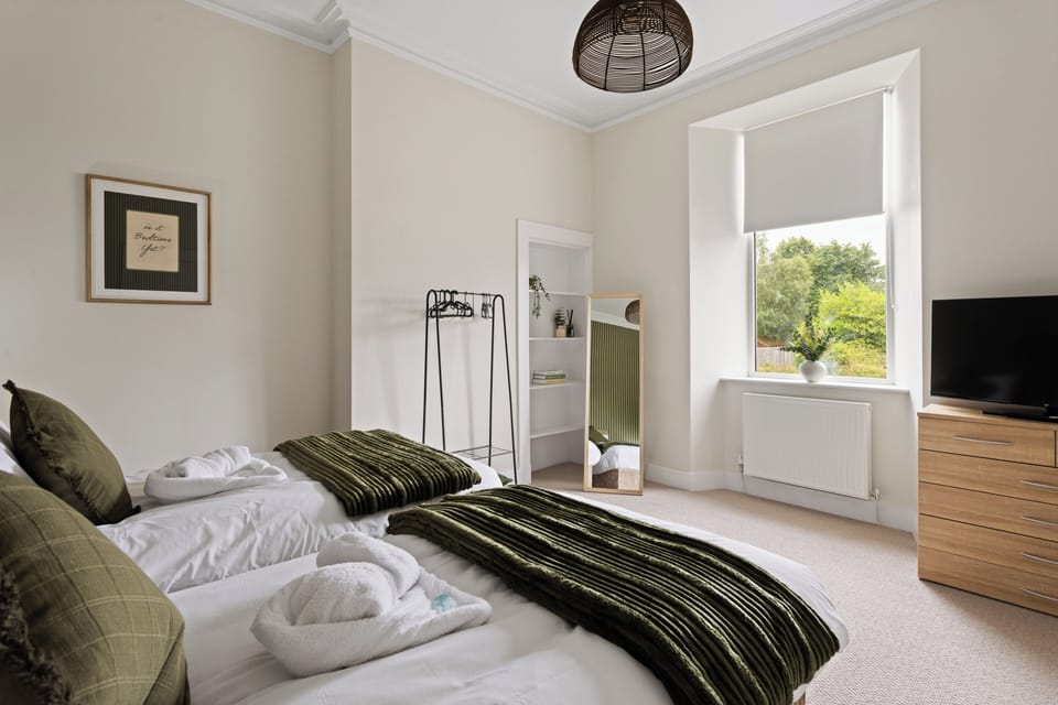 Bright twin bedroom with two comfortable beds, fresh linens, useful storage and plenty of natural daylight.