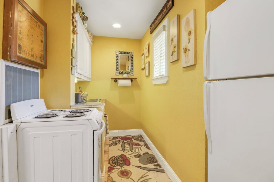 The compact full kitchen with cheerful yellow walls and vintage-inspired décor makes meal prep feel less like a chore and more like home.