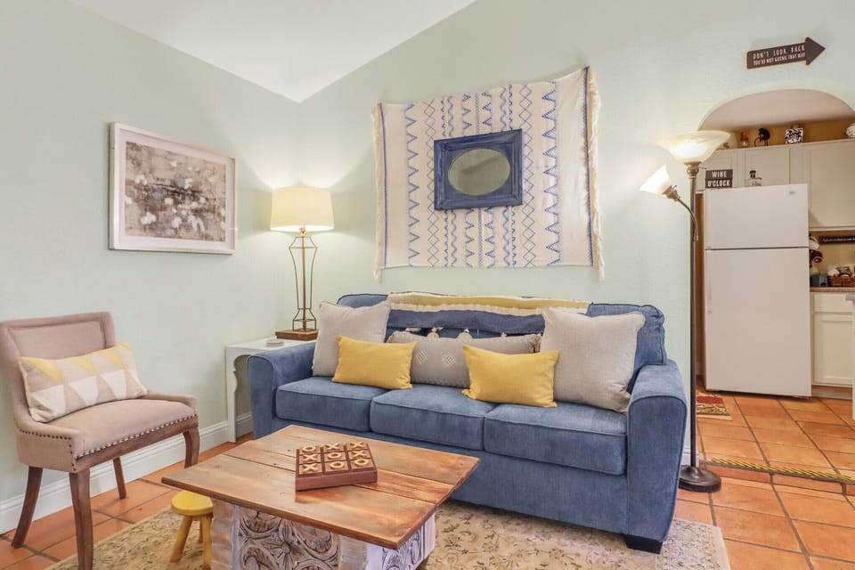 Sink into the plush blue sofa in this bright, eclectic living room where vibrant textiles and warm Saltillo tile floors create a relaxed, artistic retreat for your stay.