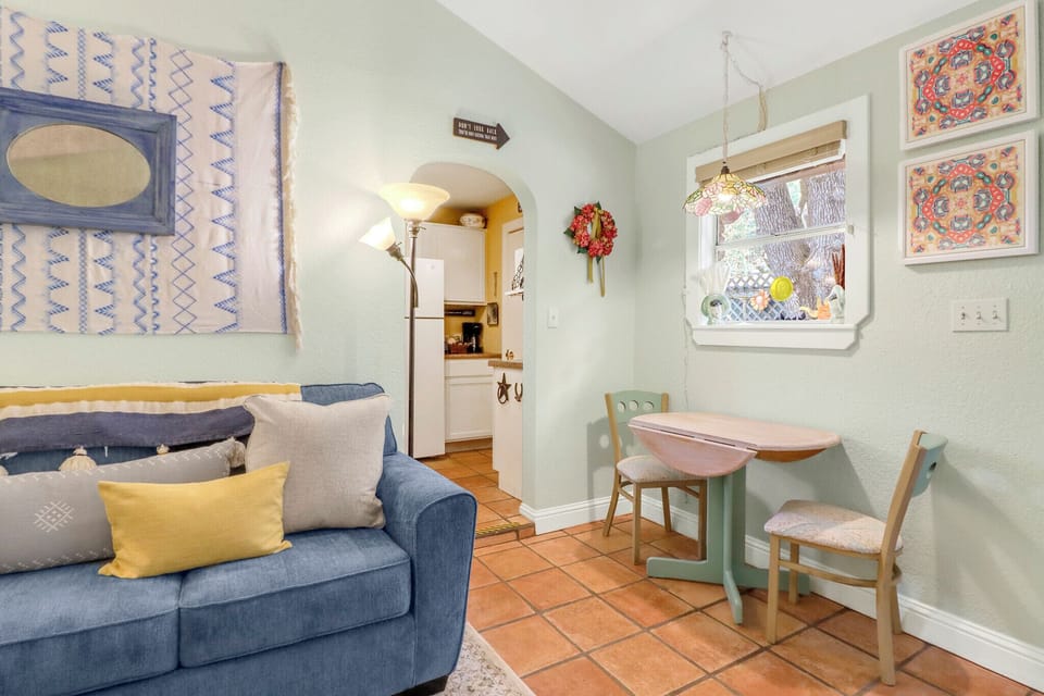 Unwind in this bright, thoughtfully decorated space featuring a cozy sofa, charming dining nook, and glimpses of the fully-equipped kitchen—perfect for your home-away-from-home getaway.