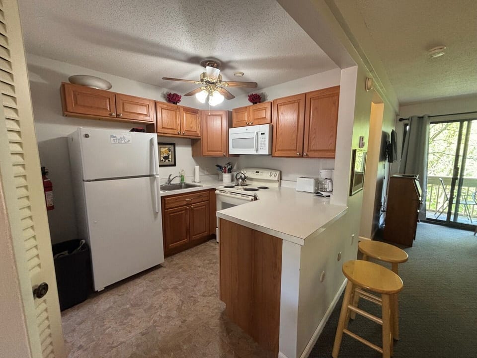 Kitchen, with bar stools. Primary bedroom off the Kitchen